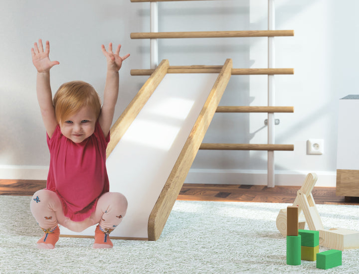 Kind rutscht das Rutschenmodul der Sprossenwand im Home Gym